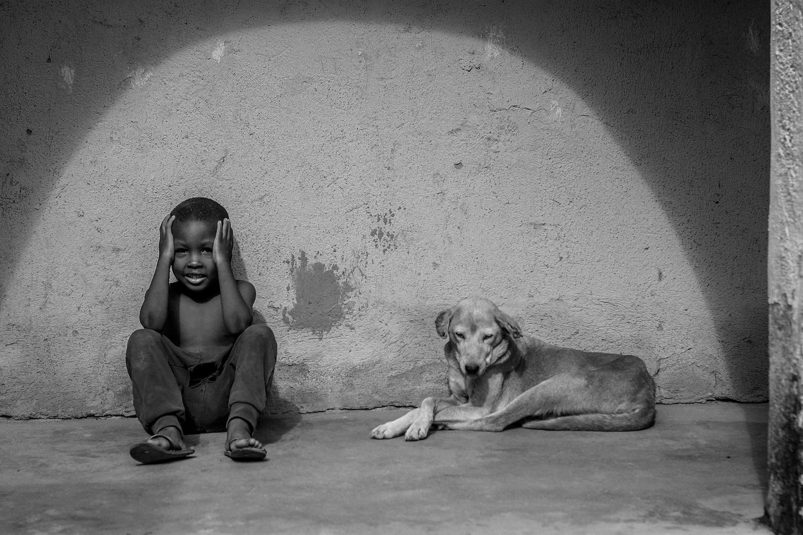 A boy and a dog sitting in front of a wall